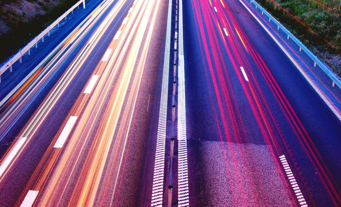 Overhead shot of a highway at night with bright lines depicting fast cars